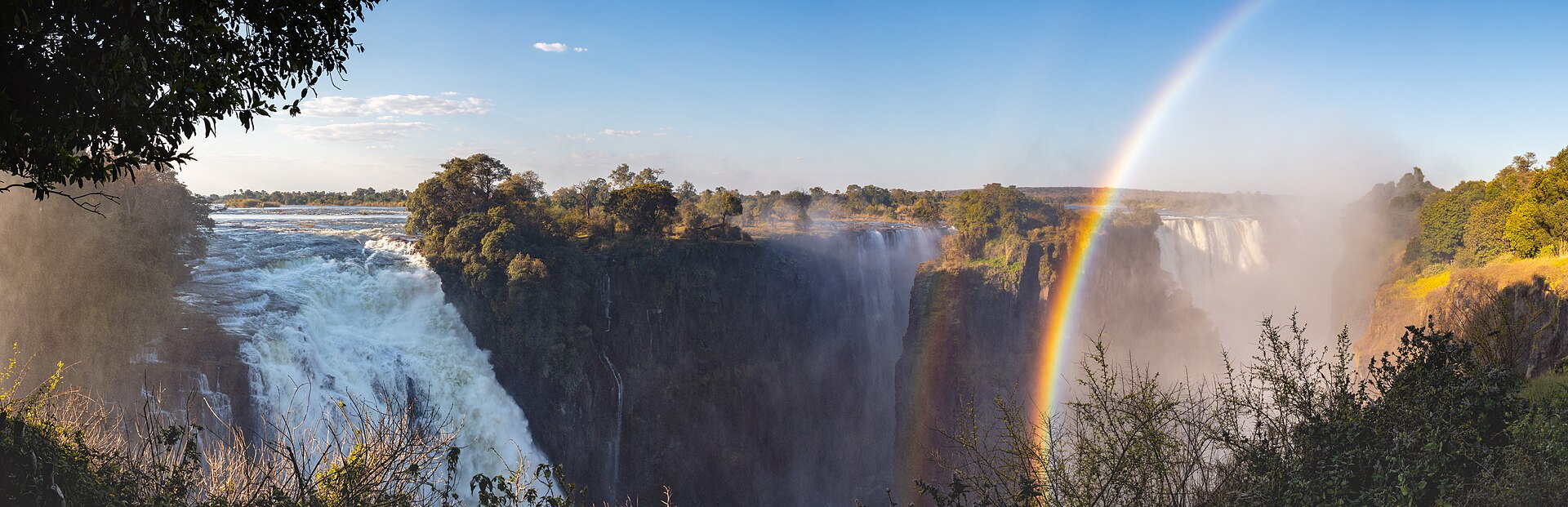 View of the Victoria Falls of the Zambezi River , border between Zambia (left side) and Zimbabwe (right side). The Victoria Falls is the largest sheet of falling water in the world based on its combined width of 1,708 metres (5,604 ft) and height of 108 metres (354 ft).
